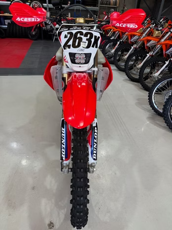 Red motocross bike with number 263 in a showroom, flanked by other dirt bikes.