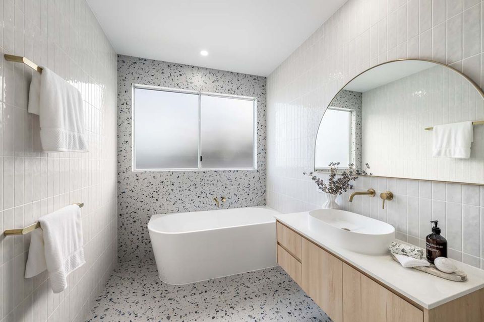 Bright modern bathroom with freestanding tub, wood vanity, round mirror, and tiled walls  — Suncoast Kitchens In Kunda Park, QLD