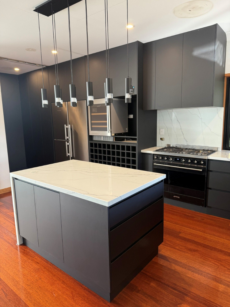 Modern kitchen with dark cabinets, white island, pendant lights, and wood floors— Suncoast Kitchens In Kunda Park, QLD