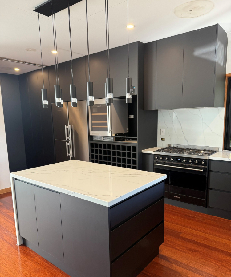 Modern kitchen with dark cabinets, large island, pendant lights, and stainless steel appliances— Suncoast Kitchens In Kunda Park, QLD