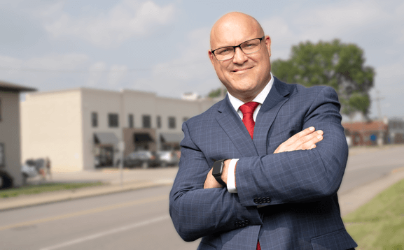 A man in a suit and tie is standing with his arms crossed.
