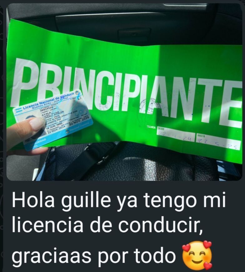 Persona sosteniendo una licencia de conducir frente a un letrero verde de “Principiante” en un auto.