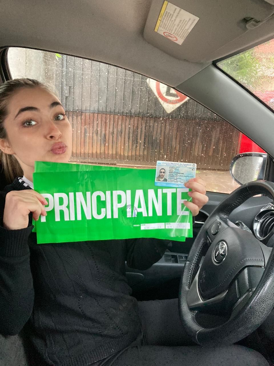 Una persona en un coche sostiene un cartel verde que dice 