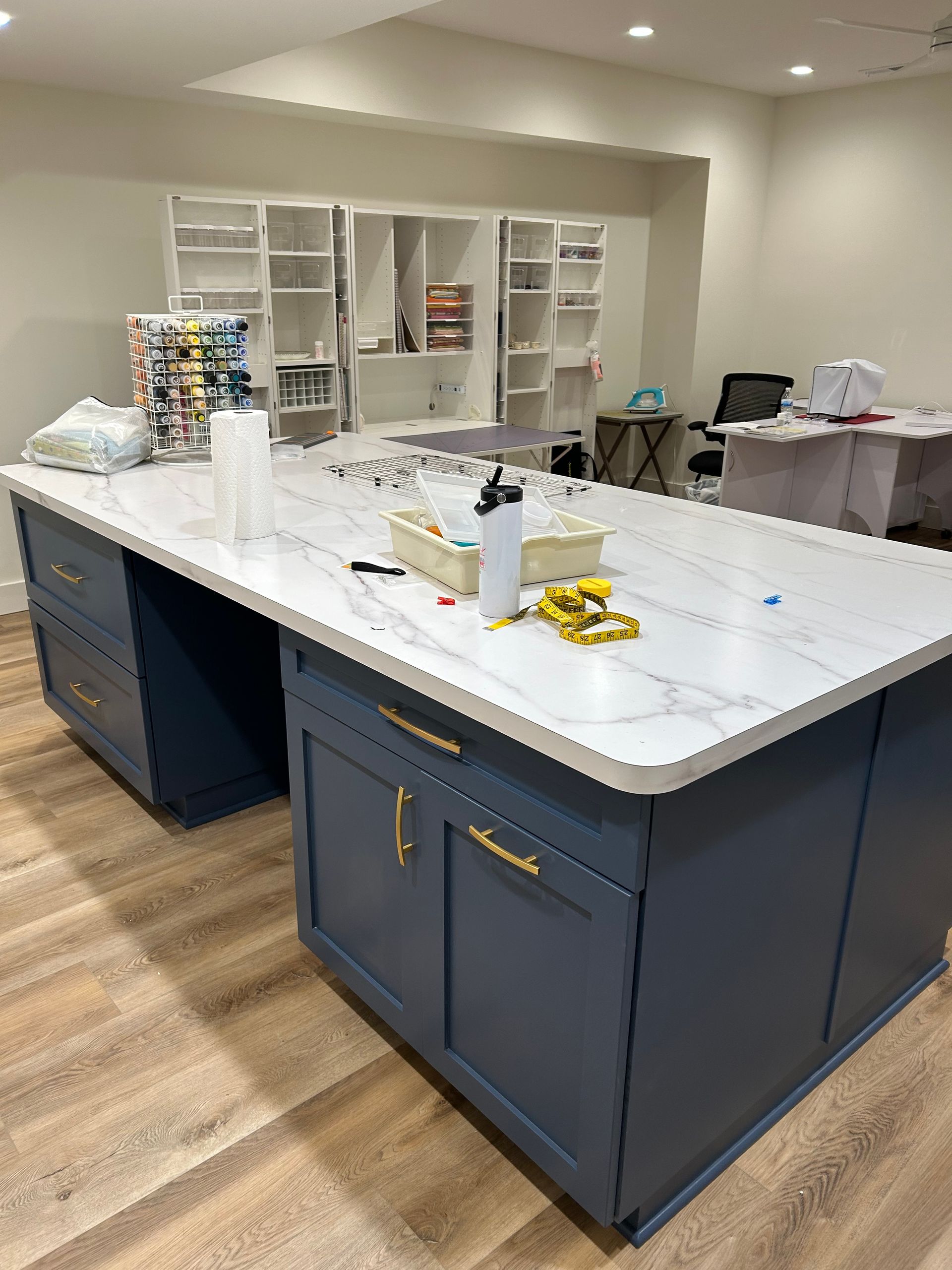 Kitchen island with blue cabinets and white countertop in a bright, mostly empty room