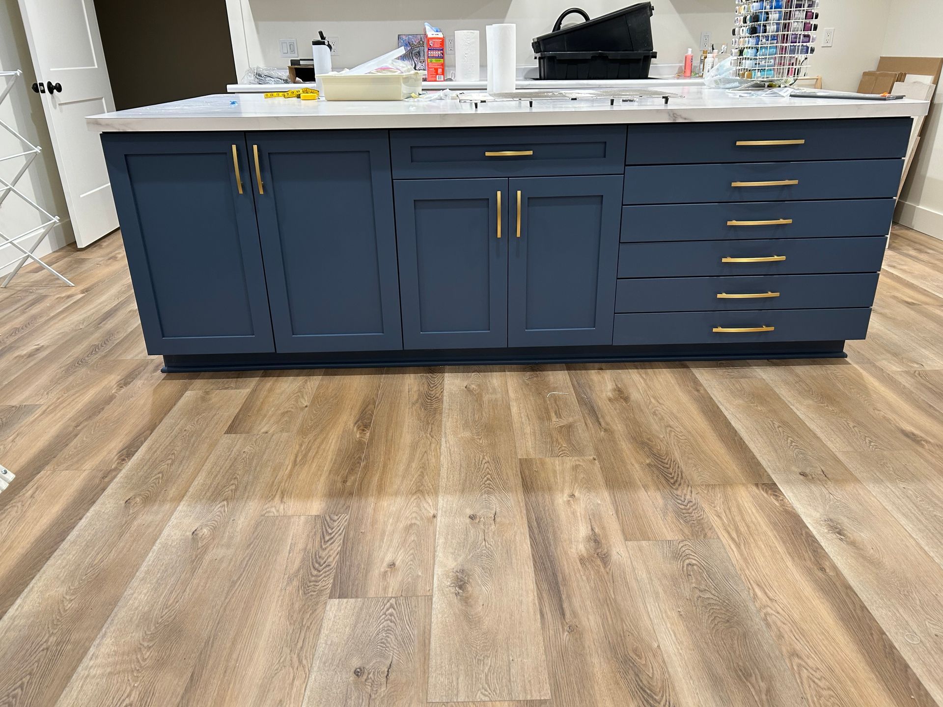 Kitchen island with dark blue cabinets and a white countertop on a wood floor
