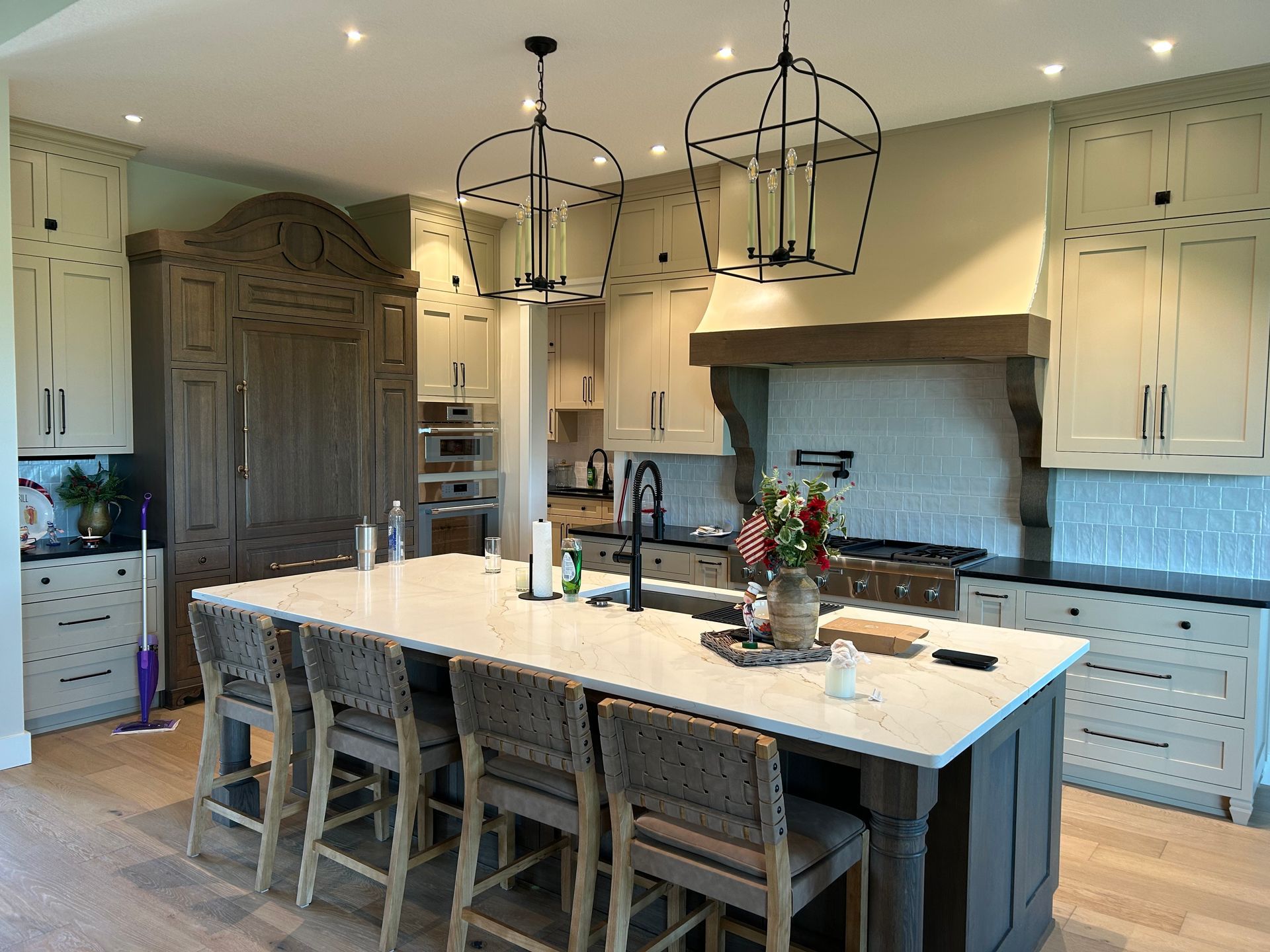 Bright modern kitchen with large island, white cabinets, pendant lights, and range hood
