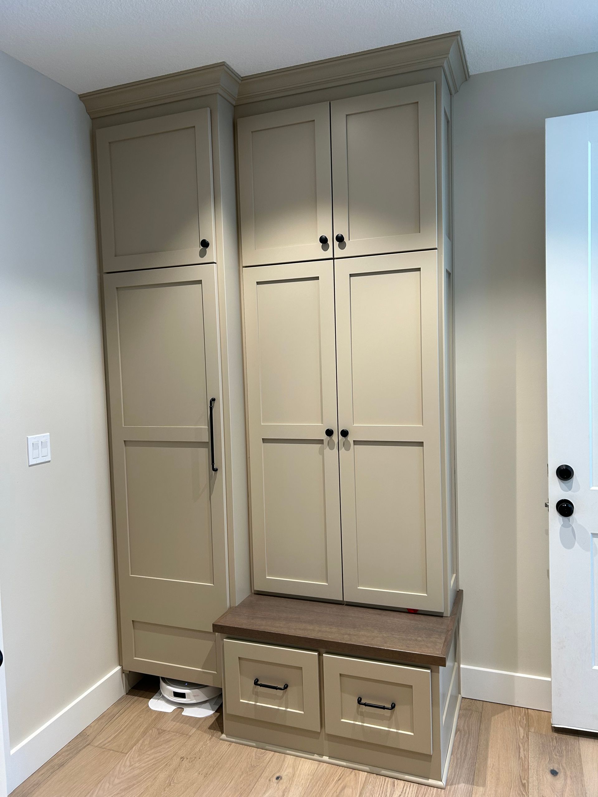 Built-in beige cabinets with bench seating and storage in a small entryway