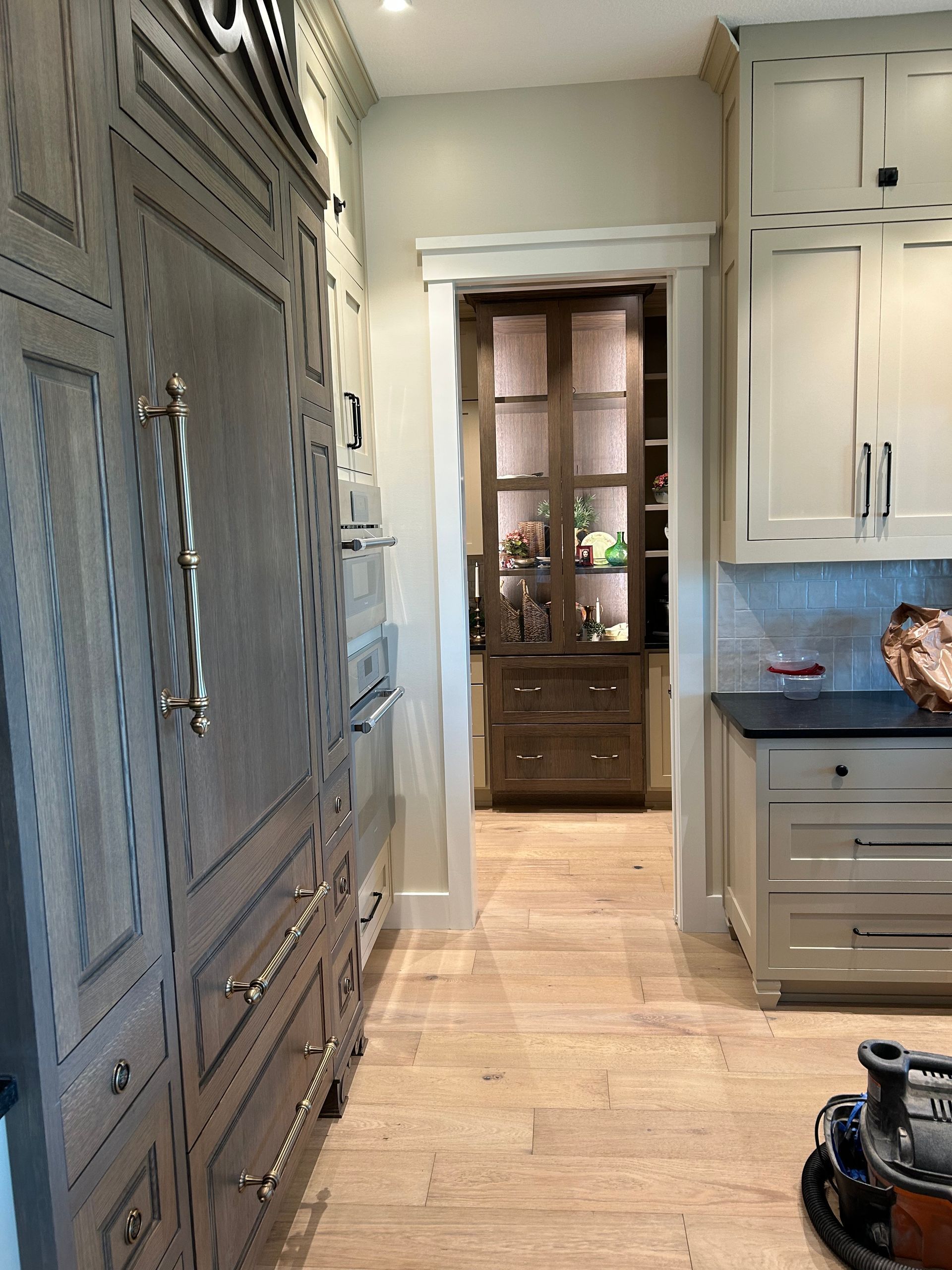 Kitchen hallway with white cabinets, gray island, and a doorway to a lit dining room.