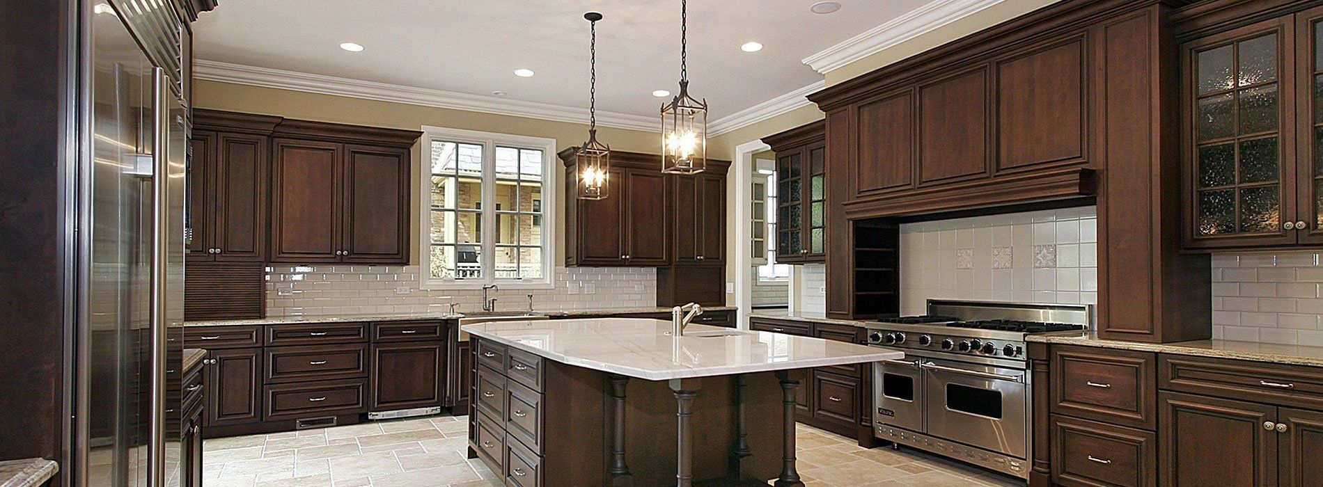 Modern kitchen with dark wood cabinets, granite island, pendant lights, and stainless steel appliances