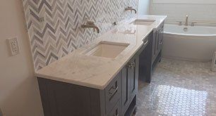 Modern bathroom with double vanity, light countertops, patterned backsplash, and a bathtub near the window.
