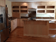 Modern kitchen with light wood cabinets, stainless appliances, center island, and hardwood floors