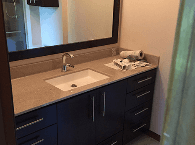 Bathroom vanity with white sink, dark cabinets, and a large mirror