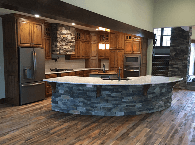 Spacious modern kitchen with wood cabinets, stainless appliances, and a stone island floor.