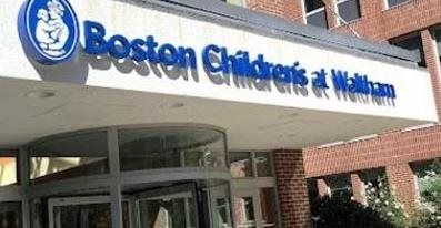 Boston Children's at Waltham building entrance with blue sign, glass doors, and brick exterior.