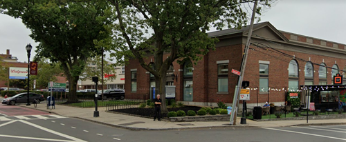 Brick building at an intersection with trees and a Walgreens sign in the background.