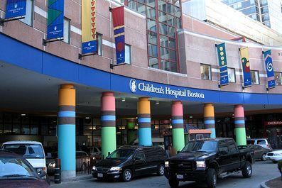 Entrance to Children's Hospital Boston with colorful pillars, blue awning, and vehicles.