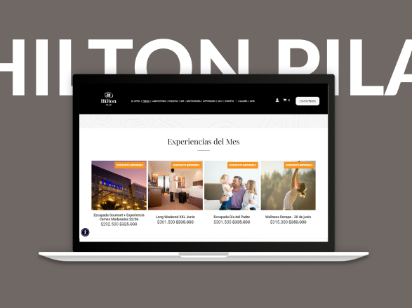 Portátil que muestra una página web de Hilton sobre un fondo marrón con un gran texto blanco detrás.