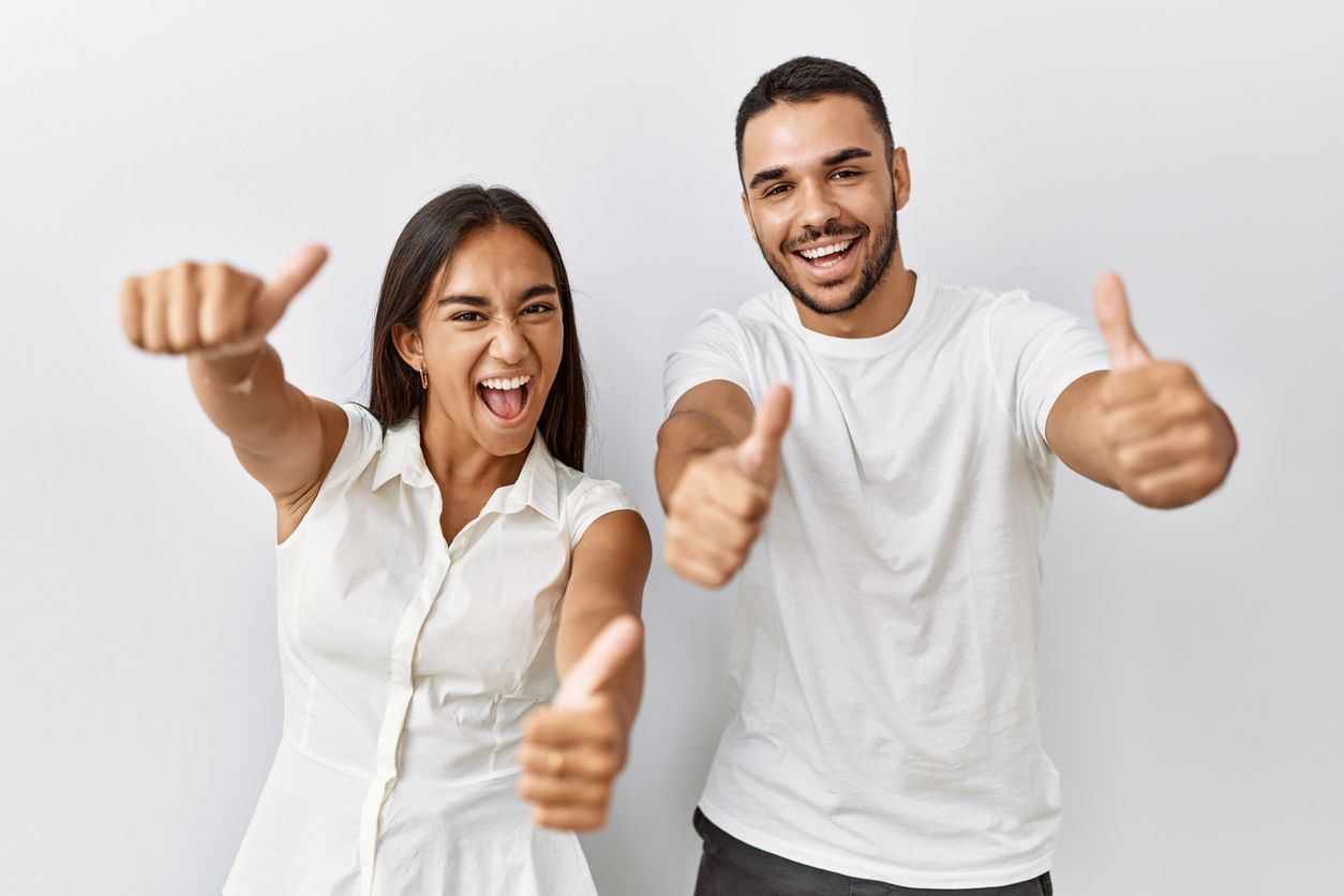 A man and a woman are giving a thumbs up sign.