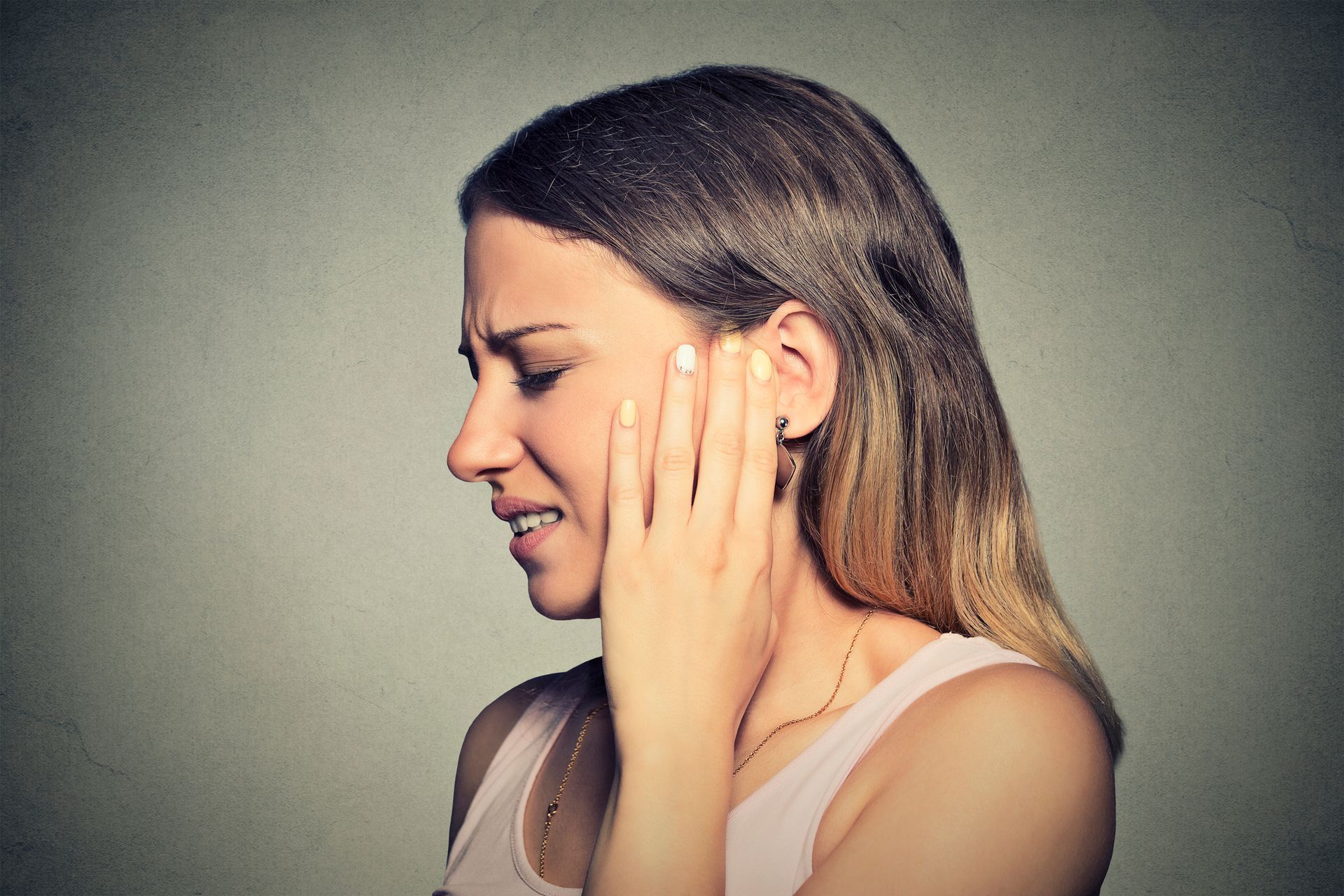 A woman is holding her ear in pain.