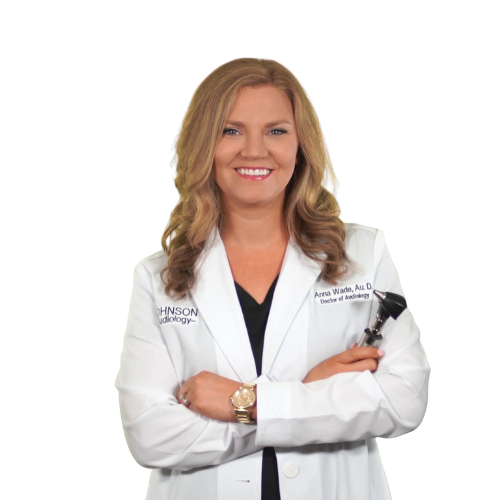 A woman in a white lab coat is smiling and holding an otoscope