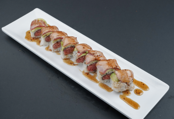 Sushi rolls drizzled with sauce on a long white rectangular plate