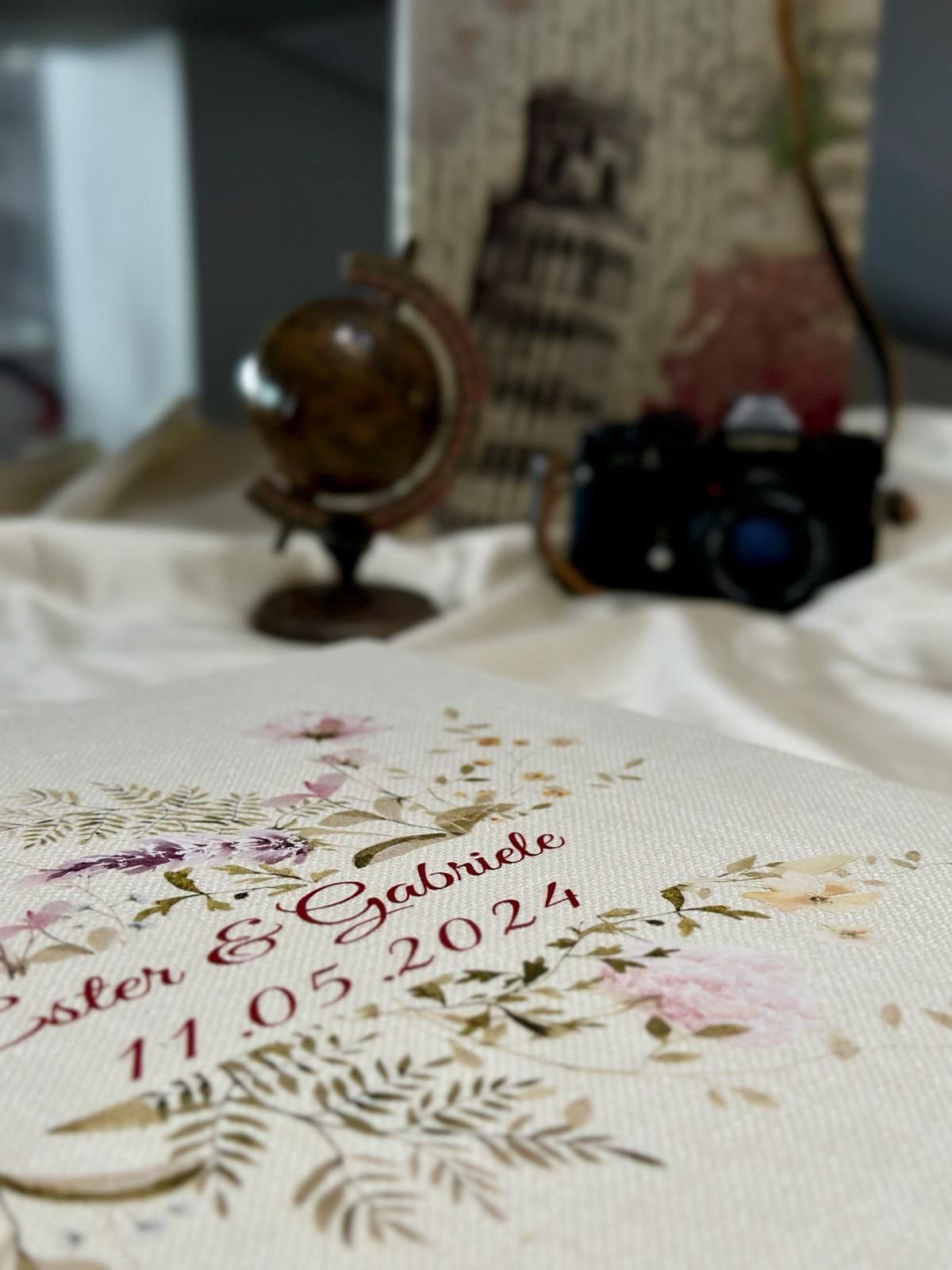 Un mappamondo è appoggiato su un tavolo accanto a una macchina fotografica e un libro.