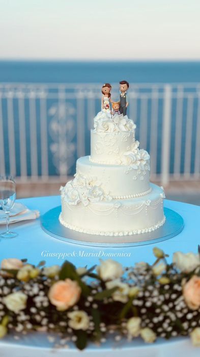 Una torta nuziale con una statuina degli sposi sopra