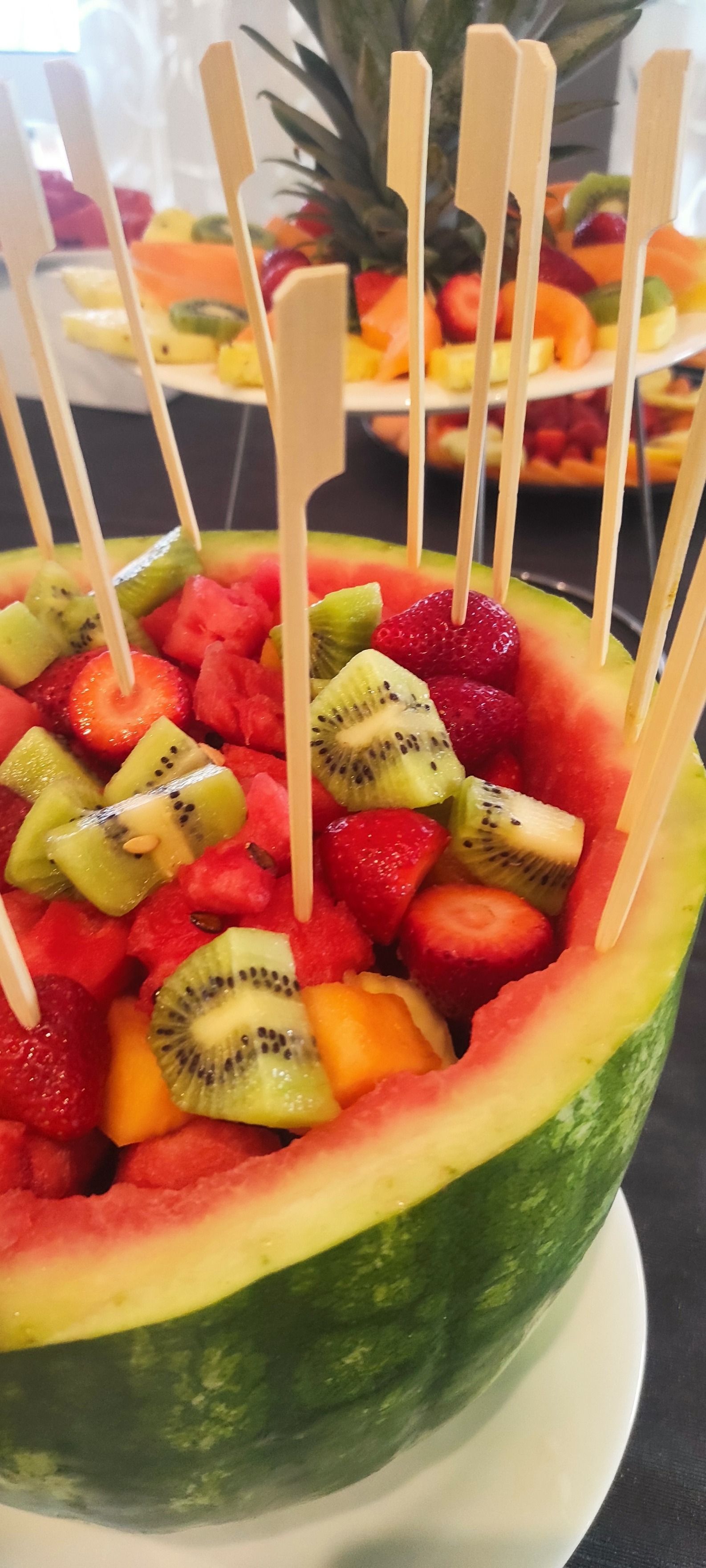 Un'anguria piena di frutta e stuzzicadenti su un tavolo.