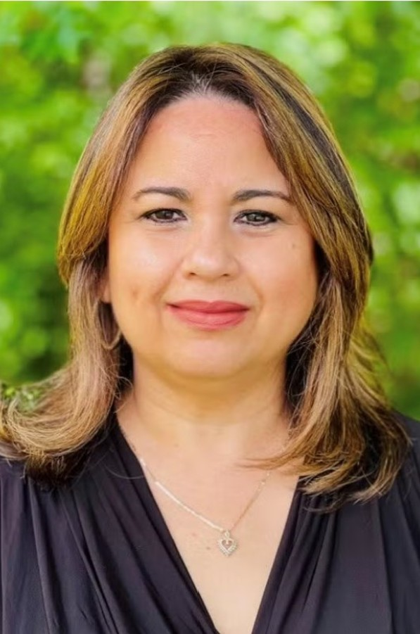 Portrait of a smiling woman in a black top against a green blurred background