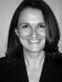 Black-and-white headshot of a smiling woman in a blazer, facing forward on a plain background