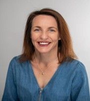 Smiling woman in a blue blouse against a light gray background