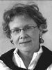 Black-and-white headshot of a person with glasses and curly hair, wearing a collared shirt and jacket.