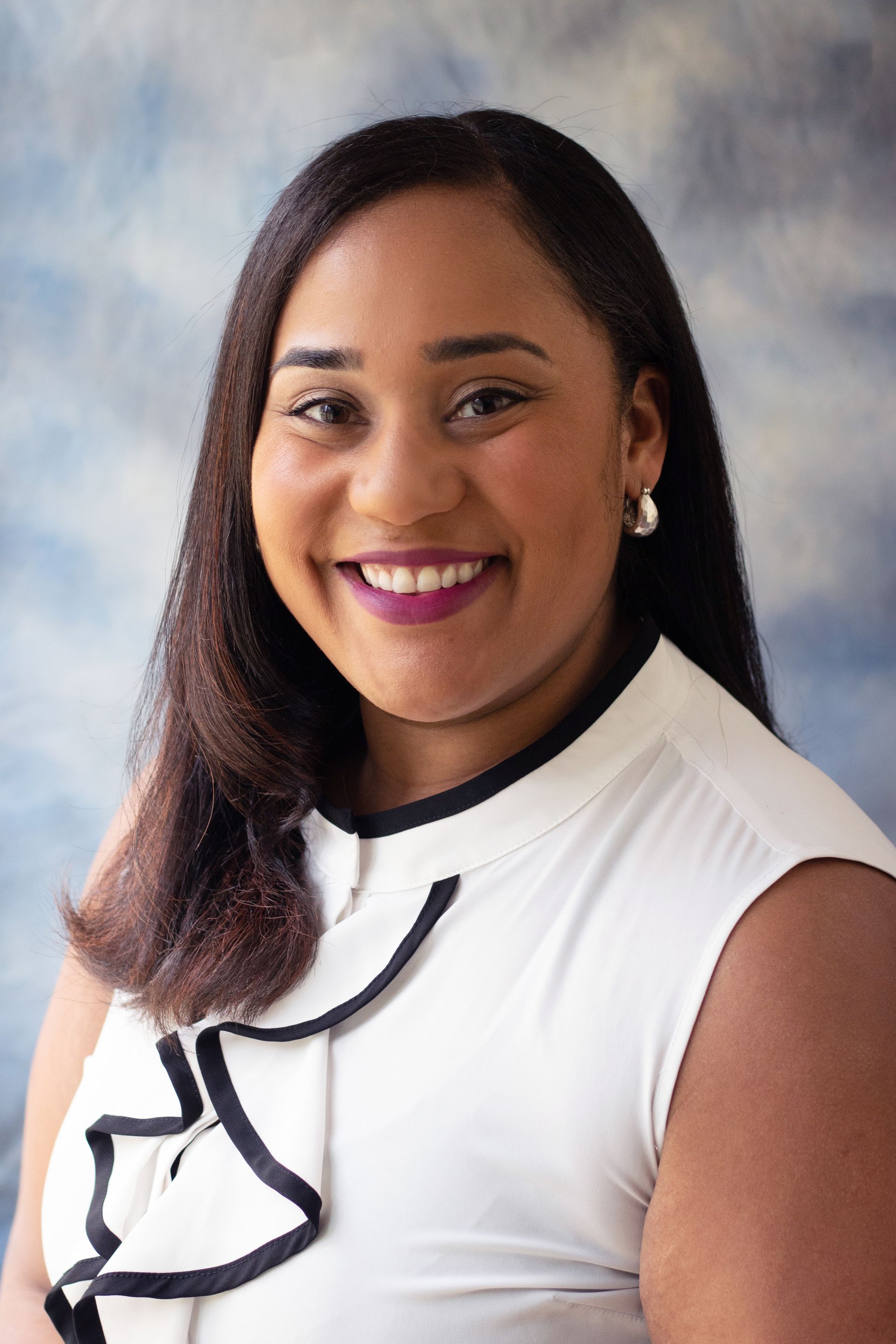 Portrait of a smiling woman in a white blouse against a soft gray studio background