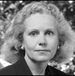 Black-and-white headshot of a woman with curly hair, looking directly at the camera.