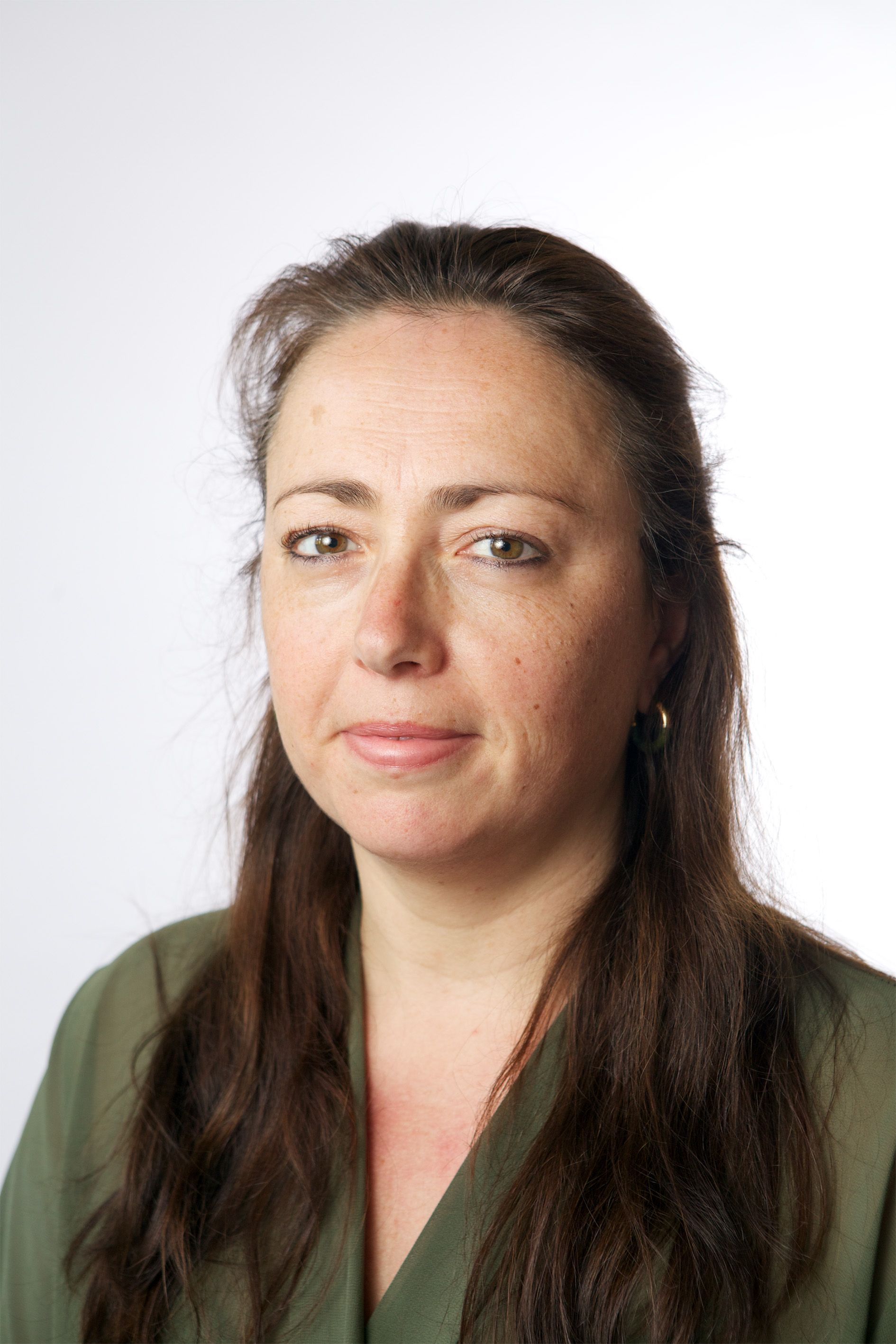 Portrait of a woman with long dark hair, wearing a green top against a white background