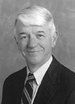 Black-and-white portrait of a smiling man in a suit and tie