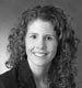 Black-and-white portrait of a smiling woman with curly hair, facing the camera.