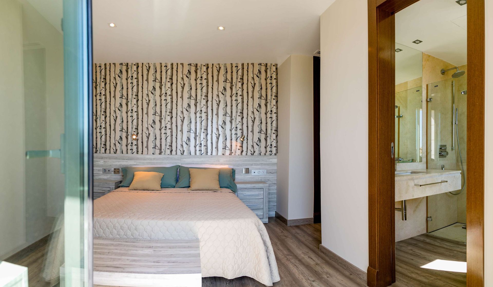 Dormitorio con pared con acento estampado, cama y entrada al baño.