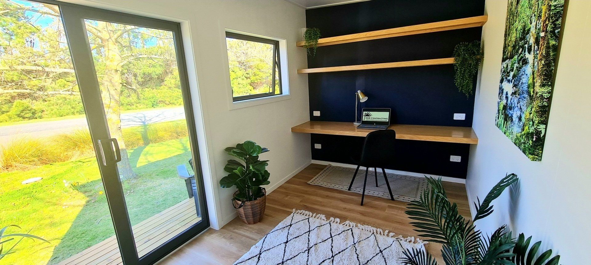 A room with a desk , chair , and sliding glass doors.