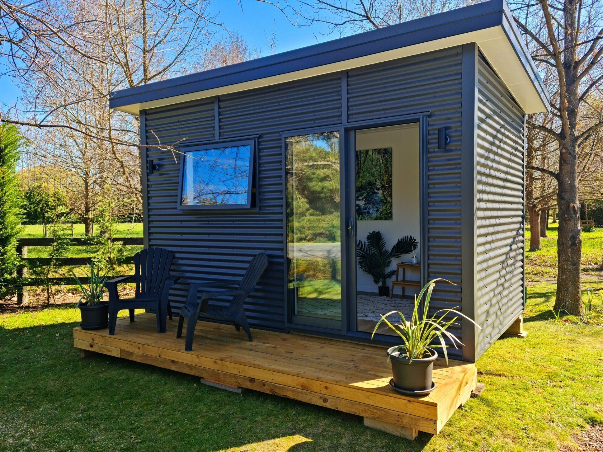 A small shed with a deck and chairs in front of it.
