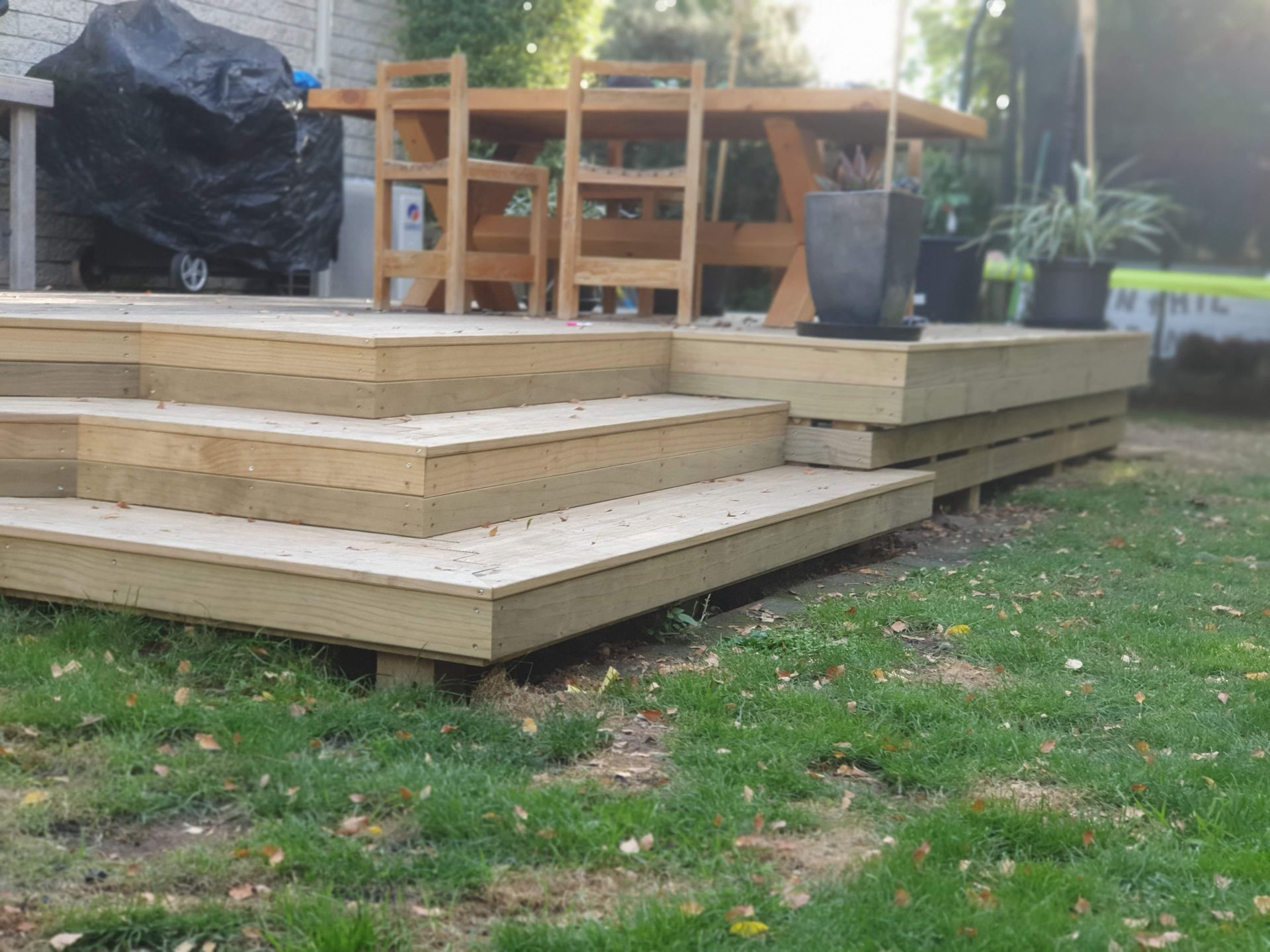 A wooden deck with stairs and a table and chairs on it.
