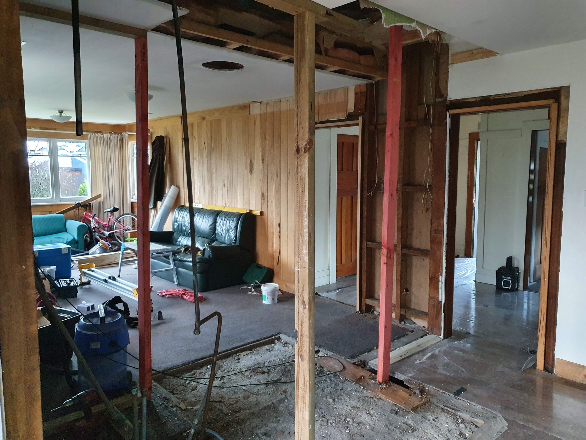 A living room under construction with a couch and a vacuum cleaner.