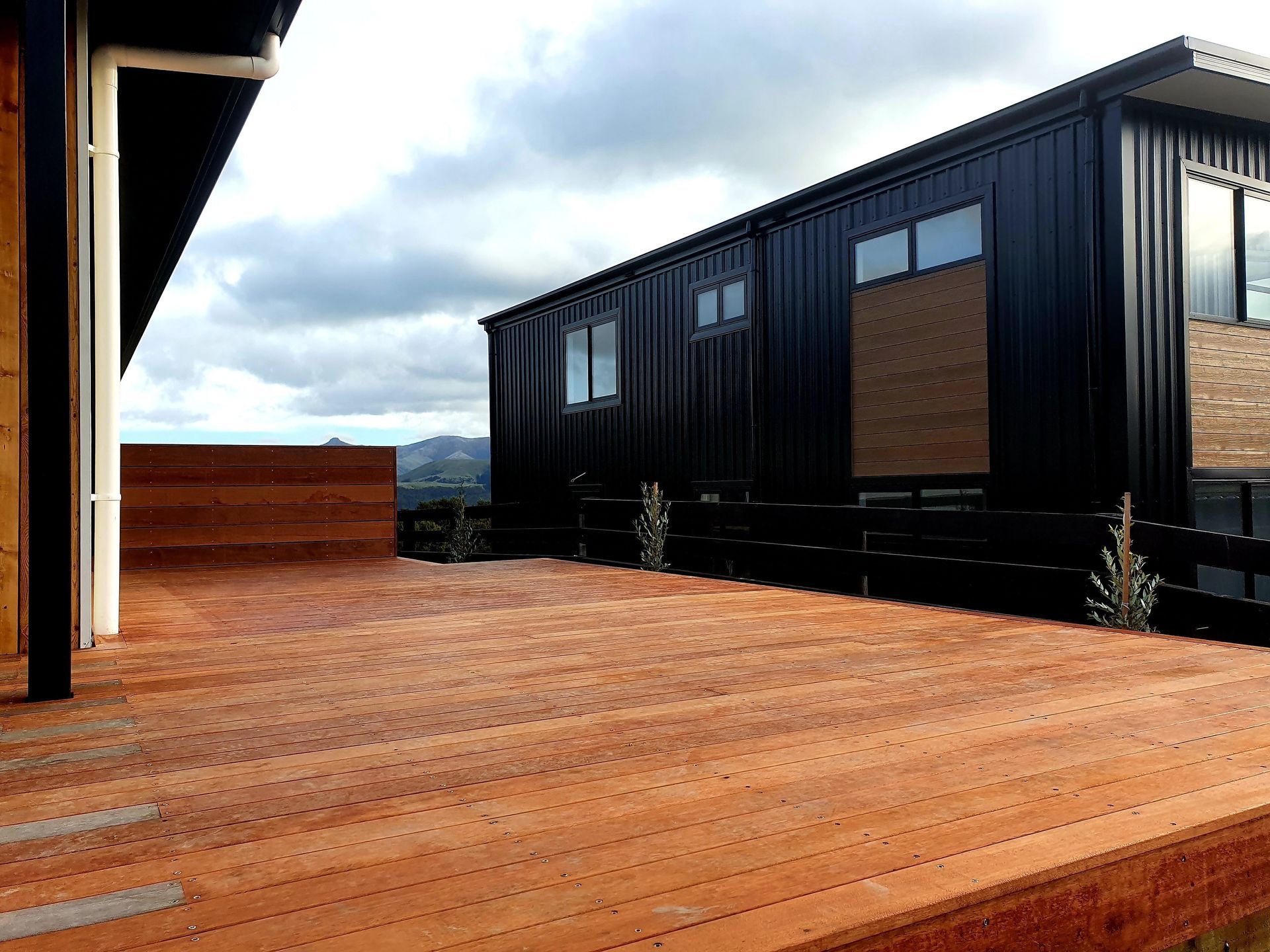 A wooden deck with a black building in the background.