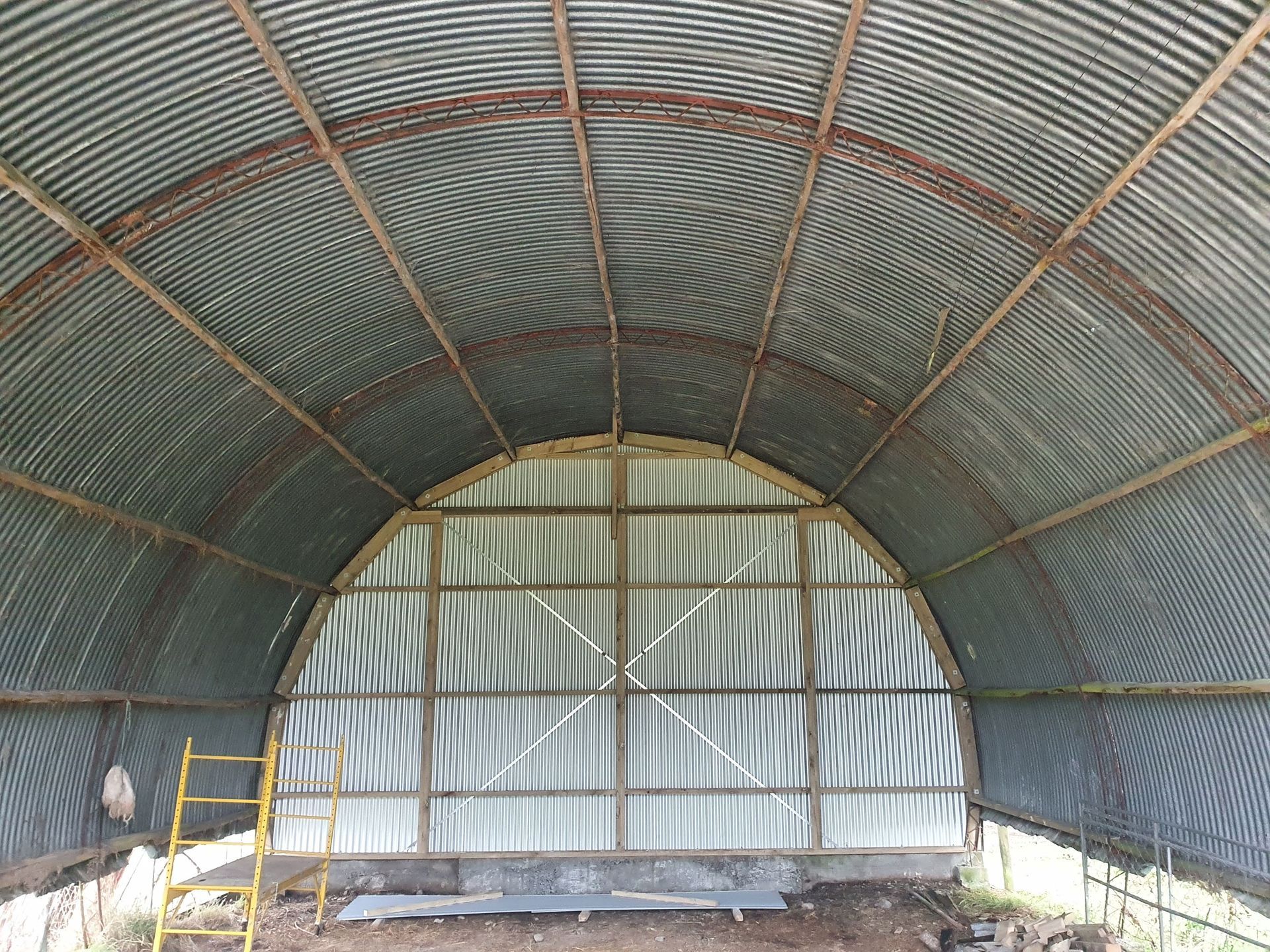 The inside of a large metal building with a wooden frame.