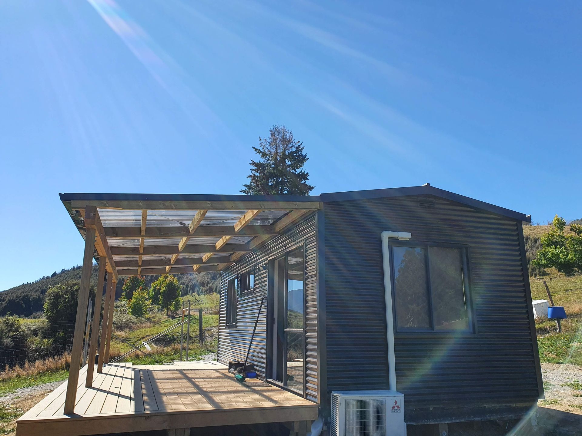 A small house with a wooden deck and a small air conditioner.