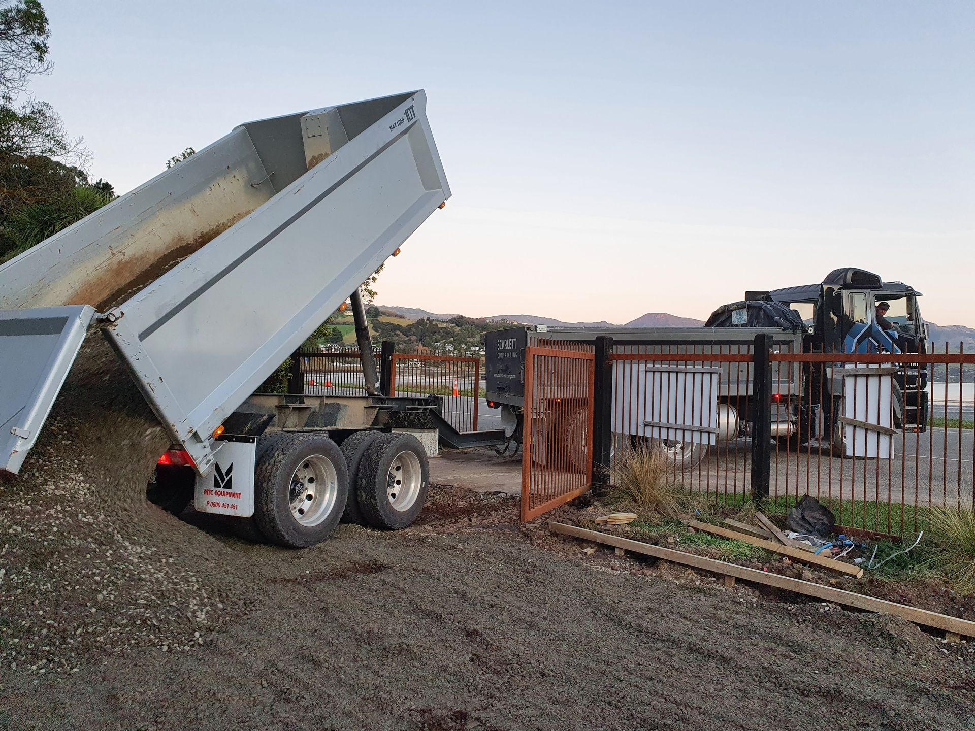 A dump truck is being loaded with gravel in a parking lot.