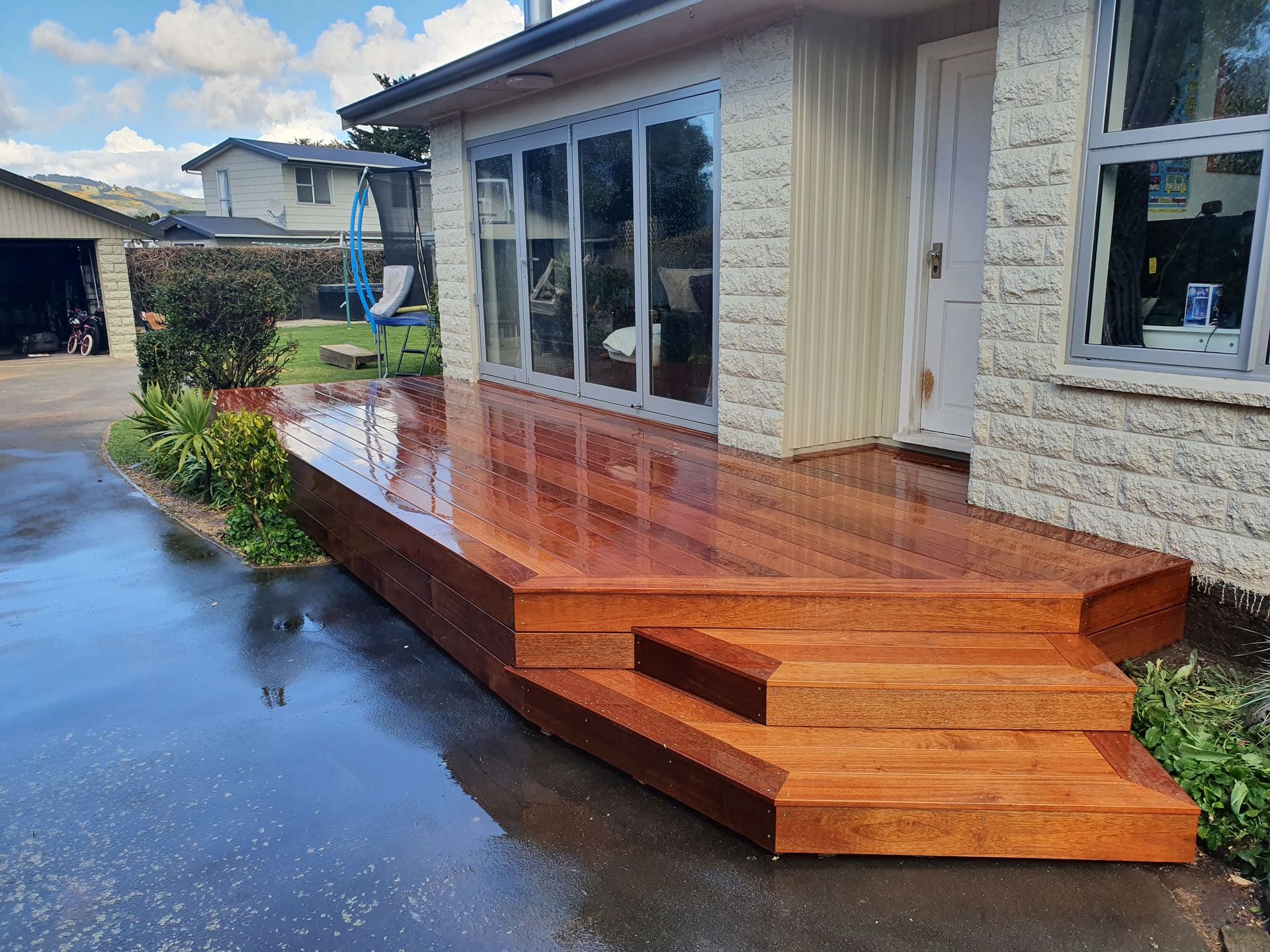 A wooden deck with stairs is in front of a house.