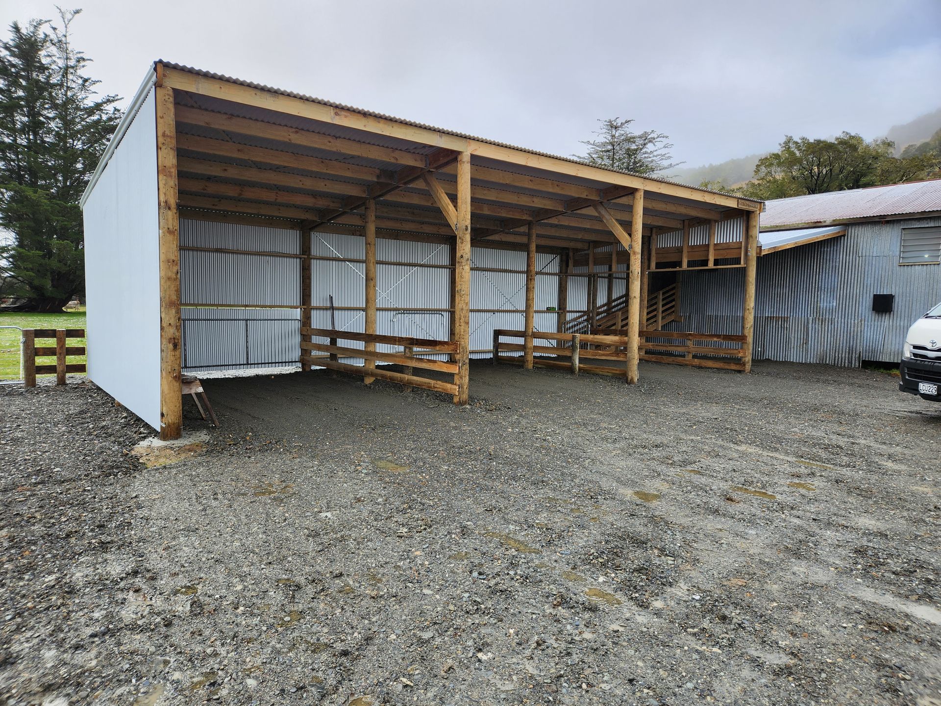 A car is parked in front of a building with a wooden roof.