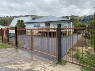 A house with a fence around it and a driveway in front of it.