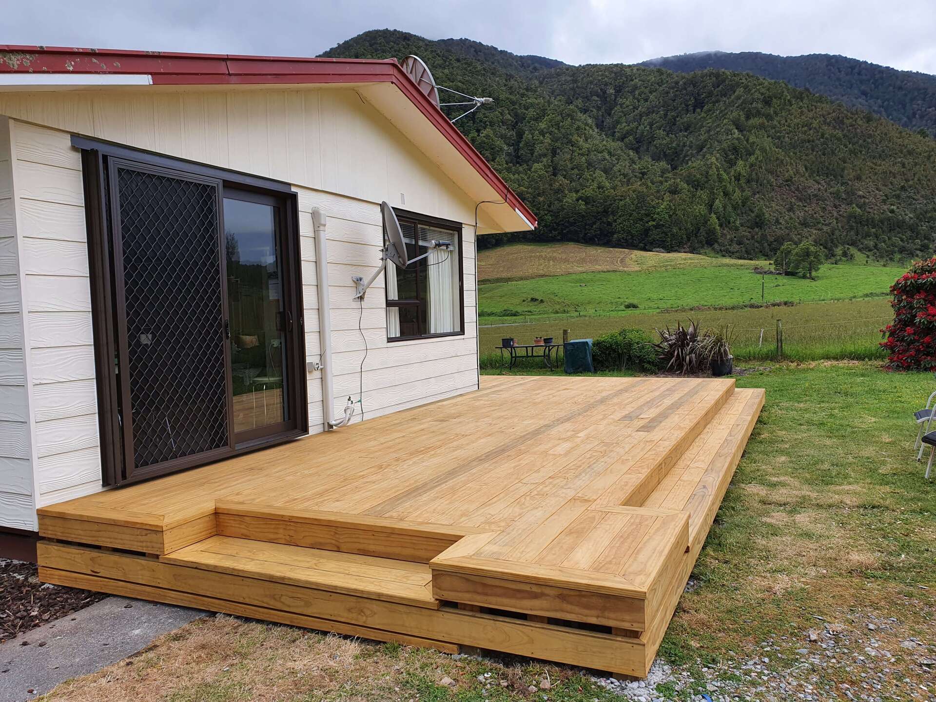 A small white house with a wooden deck in front of it.